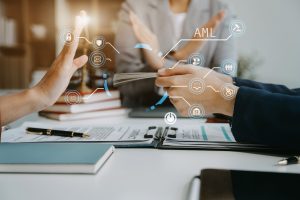 Colleges sitting at desk with AML / CTF diagrams coming out virtually from Computer